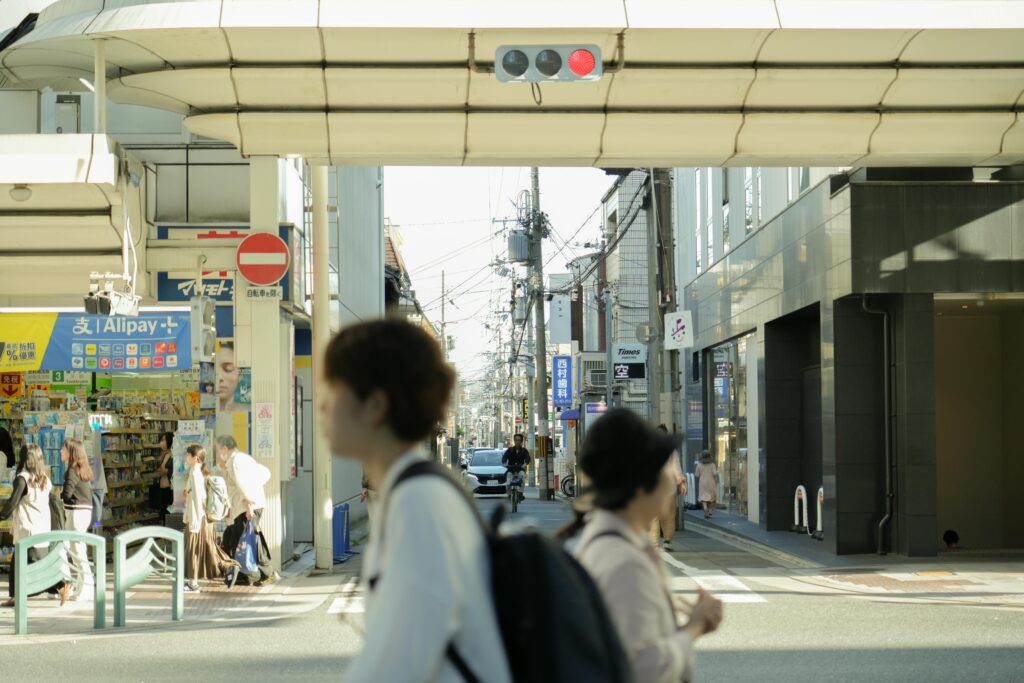 Busy street scene in Japan with pedestrians, shops, and traffic under daylight.