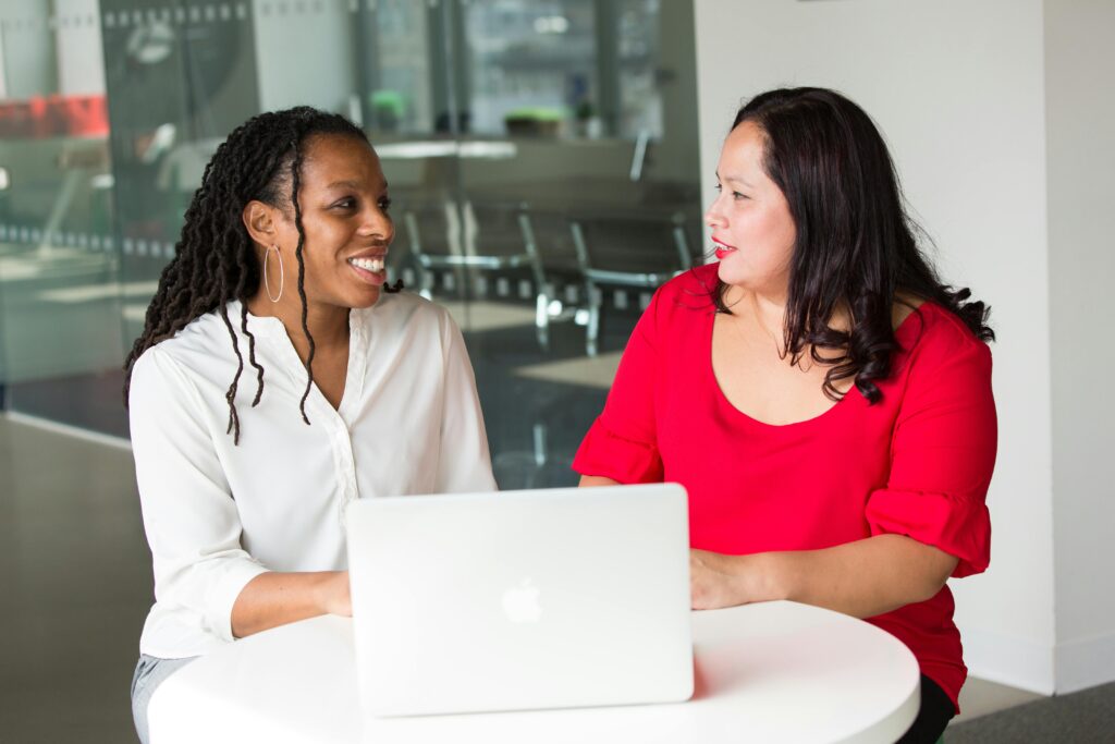 pexels photo 1181724 1181724 Two women in an office discussing work using a laptop, smiling and engaged.